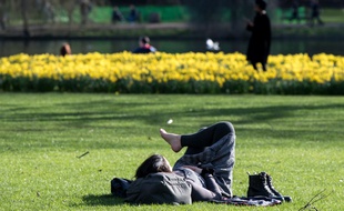 Une femme rpend le soleil dans St James Park à Londres (image d'illustration).
