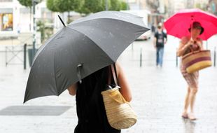 Deux femmes marchent sous la pluie avec un parapluie. Ici le 18 juillet, lors d'un orage à Rennes.