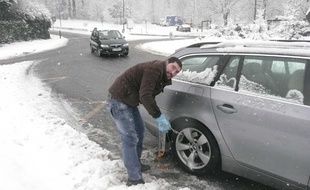 Automobiliste demontant ses chaines devenues inutiles en arrivant a Paris. La neige tombee en abondance cette nuit en Ile de France, n'a pas cause de pagaille sur les routes, moins frequentees en raison des vacances scolaires, a l'arret de circulation des camions, mais egalement grace a la prudence des automobilistes. Clamart, le 20 décembre 2010.