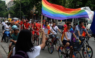 Participants in Vietnam's gay pride parade ride bicycles along a street in downtown Hanoi on August 3, 2014. Some 300 people joined a colourful bike parade throught the streets of Hanoi to show support for gay rights, with no move by communist authorities to prevent the unusual public gathering. AFP PHOTO/HOANG DINH Nam