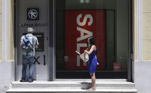 Une femme attend pour retirer de l'argent à un distributeur automatique, le 13 juillet 2015 à Athènes