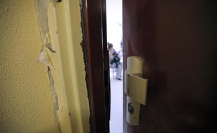 La porte fracturée d'un appartement de Fleury-Mérogis, en banlieue parisienne, où la police a perquisitionné dans le cadre de l'enquête sur les attentats djihadistes de Paris, le 16 janvier 2015