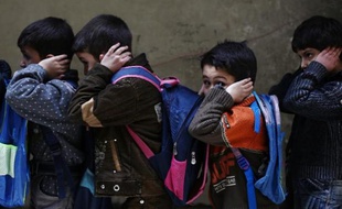 Des enfants se couvrent les oreilles lors d'un exercice d'évacuation dans une école de Douma, bastion des rebelles syriens, organisé par le Croissant rouge syrien le 11 décembre 2014