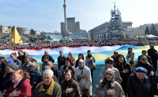 Des manifestants chantent l'hymne ukrainien devant deux drapeaux géants de l'Ukraine et de la Crimée, sur la place de l'Indépendance à Kiev le 23 mars 2014