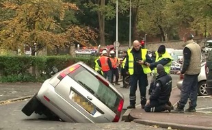 Capture d'écran d'une vidéo montrant une voiture enfoncée dans la chaussée à Saint-Germain-en-Laye, dans les Yvelines, après la rupture d'une canalisation, le 21 novembre 2013.