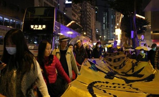 Une centaine de militants pro-démocratie manifestent dans les rues de Hong Kong portant une bannière de plusieurs mètres qui reprend leur revendication principale: "Nous voulons un vrai suffrage universel", le 24 décembre 2014