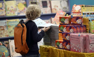 A child looks at a book during the 30th addition of the Salon du Livre et de la Presse Jeunesse (Montreuil Book and Youth Press Fair) one of the leading exhibitions for children and young people in France on November 26, 2014 in Montreuil, northeast of Paris. AFP PHOTO / STEPHANE DE SAKUTIN