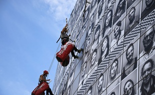 Des ouvriers installent les portraits de soignants réalisé par l'artiste JR sur l'Opéra Bastille pour l'opération #ProtegeTonSoignant .