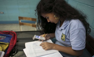 Une collégienne utilise son smartphone pour vérifier des informations relatives à ses devoirs