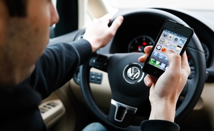 Un homme avec un téléphone au volant de sa voiture. Illustration.