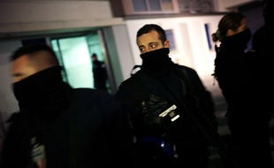 Un policie monte la garde pendant une perquisition dans un appartement