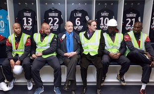 Le Maire de Bordeaux, Alain Juppé, aux côtés du président des Girondins, Jean-Louis Triaud et entouré des joueurs du club, dans les vestiaires du Nouveau stade de Bordeaux, le 23 mars 2015. AFP PHOTO / NICOLAS TUCAT