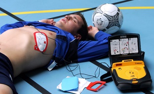 Une personne pose des électrodes d'un défibrillateur externe automatique (DEA) sur un jeune homme
