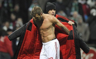 Un homme aide le milieu de terrain David Beckham à enfiler son manteau après le match opposant son équipe, le Milan AC au Werner de Brême en coupe de l'UEFA, Allemagne, le 18 février 2009.