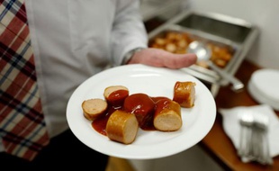 Un employé du constructeur automobile allemand Volkswagen tente une assiette de currywurst (saucisse au curry), au siège de l'entreprise à Wolfsburg en Allemagne le 21 avril 2016