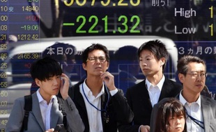 Des passants devant un tableau électronique affichant les cours de la Bourse, à Tokyo, le 14 octobre 2014