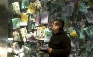 Un homme regarde une installation faite de billets de banques grand format, le 24 septembre 2013 à Prague