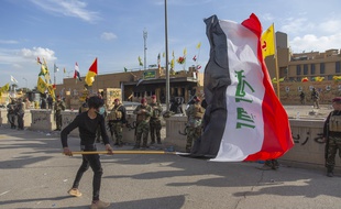 Un manifestant avec le drapeau irakien devant l'ambassade américaine de Bagdad, le 1er janvier 2020.