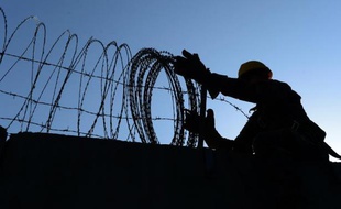 Un soldat américain retire, le 1er novembre 2014, des fils barbelés d'un mur d'enceinte de la base aérienne de l'Otan de Bagram, au nord de Kaboul