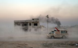 Un van abandonné surmonté d'un drapeau de l'Irak, à l'Est de Mossoul
