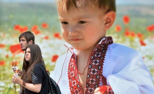Un couple passe à Kiev le 23 mai 2014, devant une affiche d'un enfant portant la traditionnelle chemise ukrainienne, deux jours avant les élections présidentielles