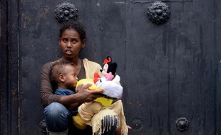 Une mère porte son enfant devant un centre d'immigration à Rome, le 14 juin 2015