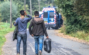 Deux migrants marchent sur le bord de la route après l'évacuation d'un campement sauvage près de Grande-Synthe en septembre 2017.