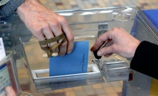 Une personne introduit son bulletin de vote dans une urne.