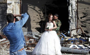 Des nouveaux mariés prennent la pose le 5 février 2016 devant le photographe Jaafar Merhi au milieu des façades soufflées par les explosions dans la ville de Homs