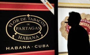 Un homme fume un cigare pendant le dîner d'ouverture du 16e Festival international du cigare à La Havane, Cuba, le 24 février 2014.