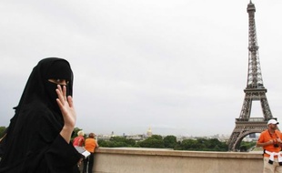 Une femme, portant le voile intégral, pose devant la tour Eiffel à Paris.