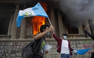 Devant le parlement en feu, un manifestant brandit le drapeau du Guatemala, le 21 novembre 2020.