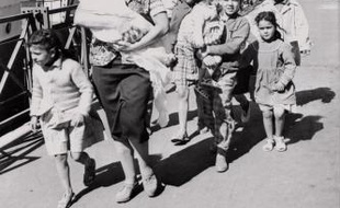 Une femme et ses enfants désireux de gagner la métropole viennent de débarquer du "Ville d'Oran" à Marseille le 26 mai 1962 comme de nombreux réfugiés notamment des Européens d'Algérie (pieds noirs) et des familles de harkis qui continuent d'affluer vers la France depuis la signature des accords d'Evian. Après plus de sept ans de guerre l'Algérie a proclamé son indépendance après la signature des accords d'Evian le 18 mars 1962 et leur ratification par référendum en France le 08 avril 1962 puis en Algérie le 1er juillet 1962.