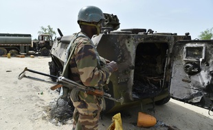 Un soldat nigérien devant un véhicule détruit lors d'une attaque de Boko Haram, le 17 juin 2016 à Bosso