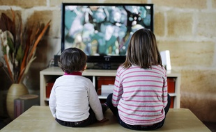 Deux enfants regardent un écran de télévision.