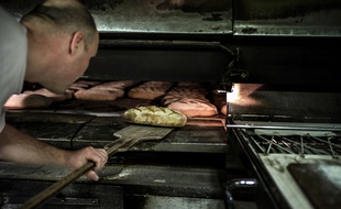 Illustration d'un boulanger mettant son pain au four à l'aide d'une pelle.