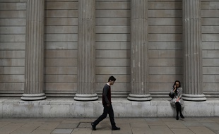 Un homme marche devant la banque d'Angleterre, à la City de Londres.