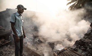 Un homme devant les ruines d'une maison encore fumante, dans le quartier PK5 le 26 décembre 2019.