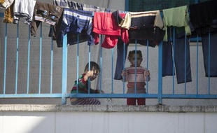 Des enfants palestiniens réfugiés dans une école à Gaza regardent du balcon la chef de la diplomatie européenne Frederica Mogherini lors de son discours, le 8 novembre 2014