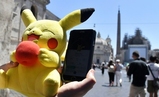 Un joueur tient une mascotte de Pokémon et joue au Pokémon Go sur son portable, le 19 juillet 2016 à Rome.