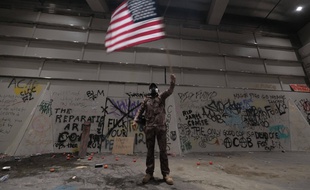 Un homme brandit un drapeau américain lors d'une manifestation devant la Cour de Justice de Portland.