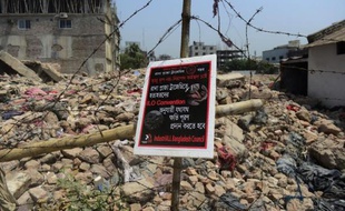 Un panneau demandant des conditions de travail correctes sur le site du bâtiment du Rana Plaza , qui s'est effondré le 23 avril 2013, photographié le 24 avril 2014 à Dacca