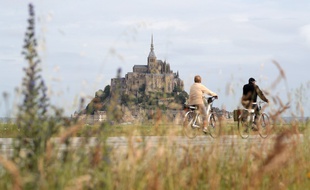 Un couple de cyclotouristes arrive au Mont-Saint-Michel, le 24 juillet 2016.