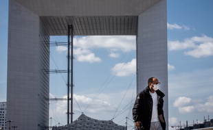Un homme portant un masque sur le parvis de La Défense.