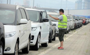 Un homme vérifie des voitures importées à Qingdao le 19 août 2015