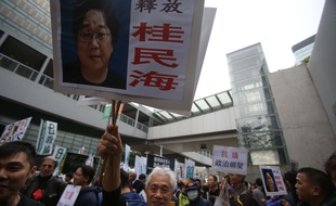 Des manifestants tiennent des panneaux à l'effigie du libraire disparu Gui Minhai, le 10 janvier à Hong Kong.