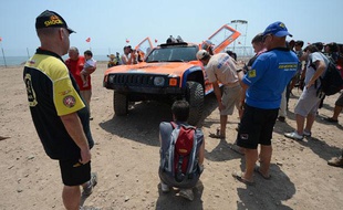 La voiture de l'Américain Robby Gordon scrutée par des mécanos des autres équipes, le 4 janvier 2013, à Lima (Pérou).