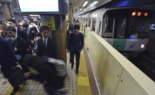 Des passagers attendant le train sur le quai d'une gare japonaise. Illustration.