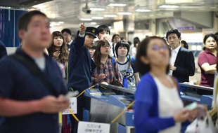 Des japonais attendent le train à grande vitesse le "Shinkansen" à une station de Tokyo alors que la circulation a été interrompue en raison d'un séisme de magnitude 7,8 à 874 kilomètres de la capitale japonaise, le 30 mai 2015