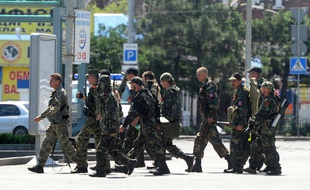 Des séparatistes armés prorusses traversent une rue à proximité de la gare de Donetsk ce lundi 21 juillet alors que des tirs d'artillerie secouent le quartier.